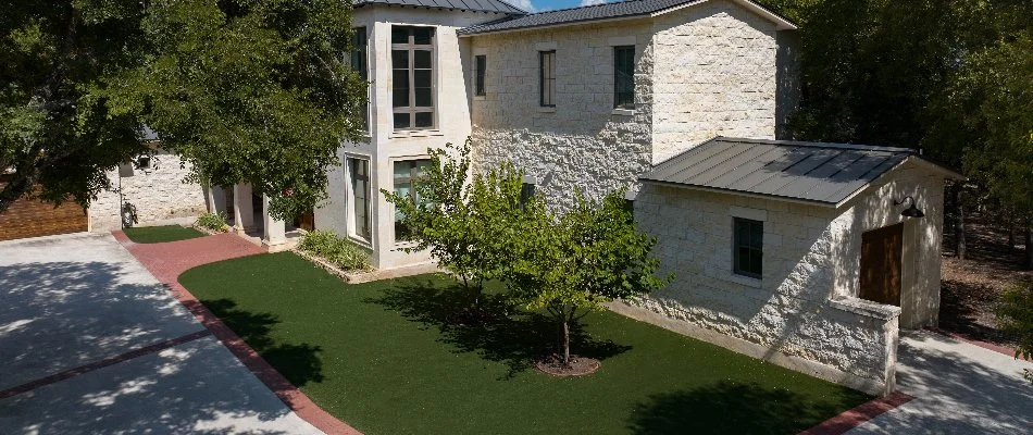 Artificial turf and trees in front of a house in New Braunfels, TX.