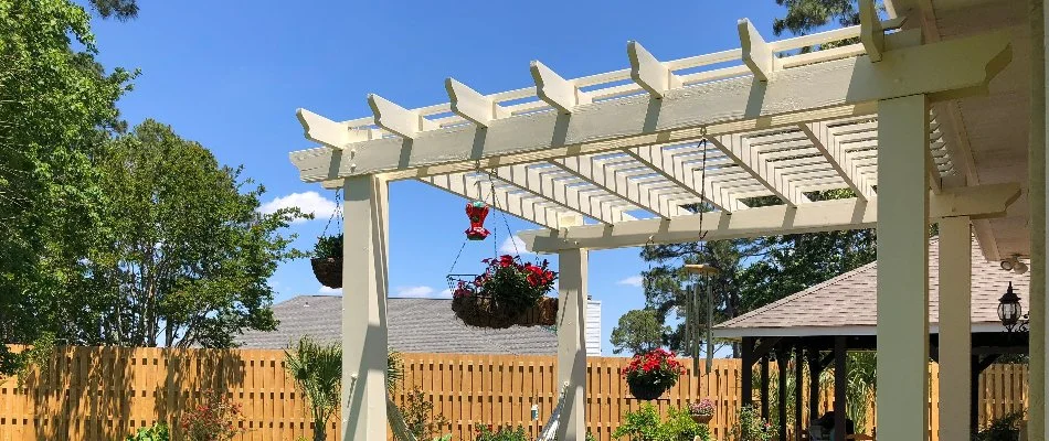 White pergola in New Braunfels, TX, with plants and flowers.